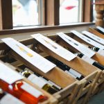 Weinflaschen mit aufgeklebten Etiketten liegen in Holzkisten